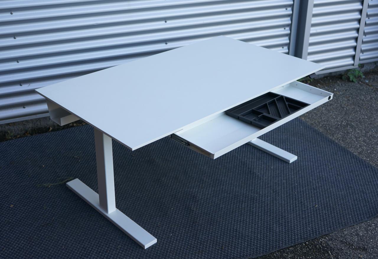 Holmris B8 hæve-sænkebord 140x80 cm i hvid med affasede kanter, kabelbakke og udtræksskuffe, set fra skrå vinkel.